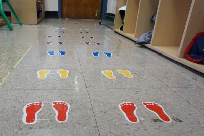 Tiny footprints taped to tile floor in classroom